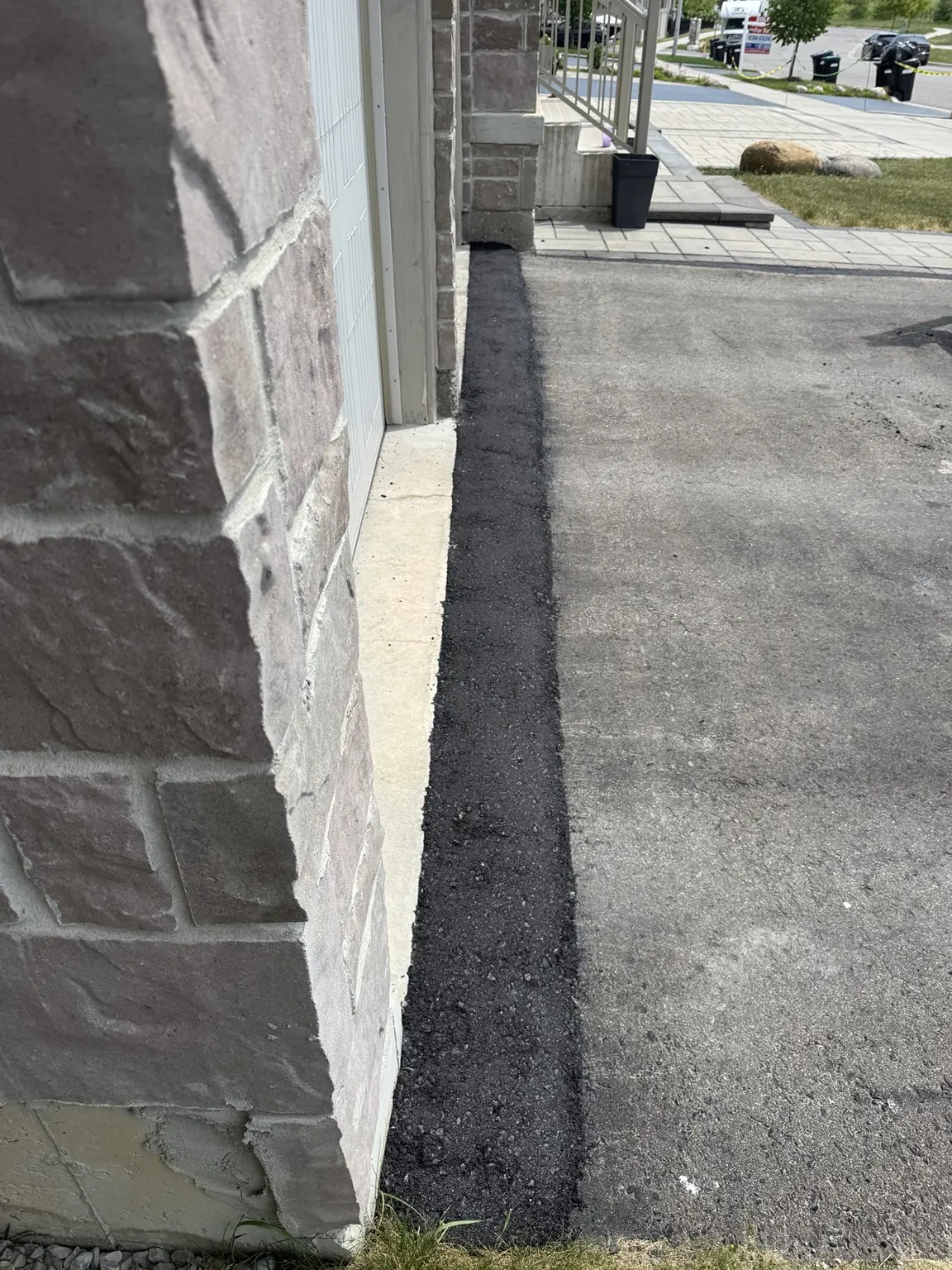Detailed asphalt repair installed along a garage edge