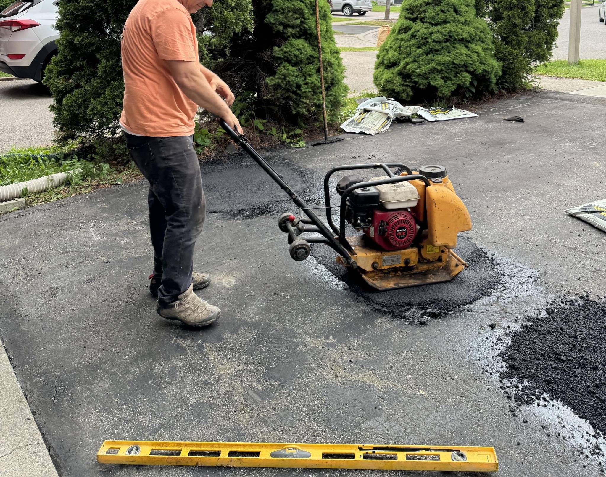 Asphalt repair with vibrating plate machine in action