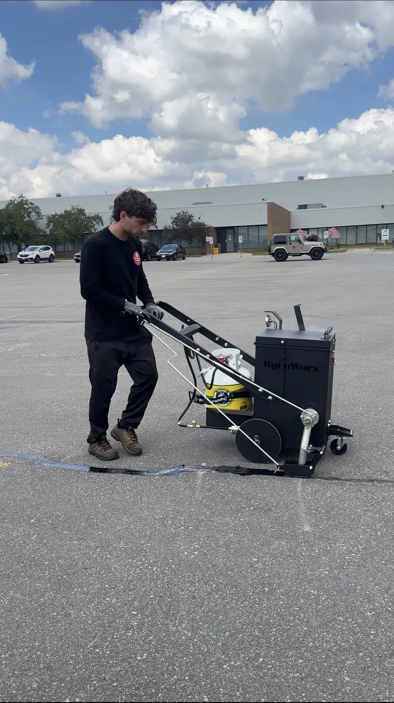 Oneway crew applying hot-rubber crack filler on a commercial parking lot