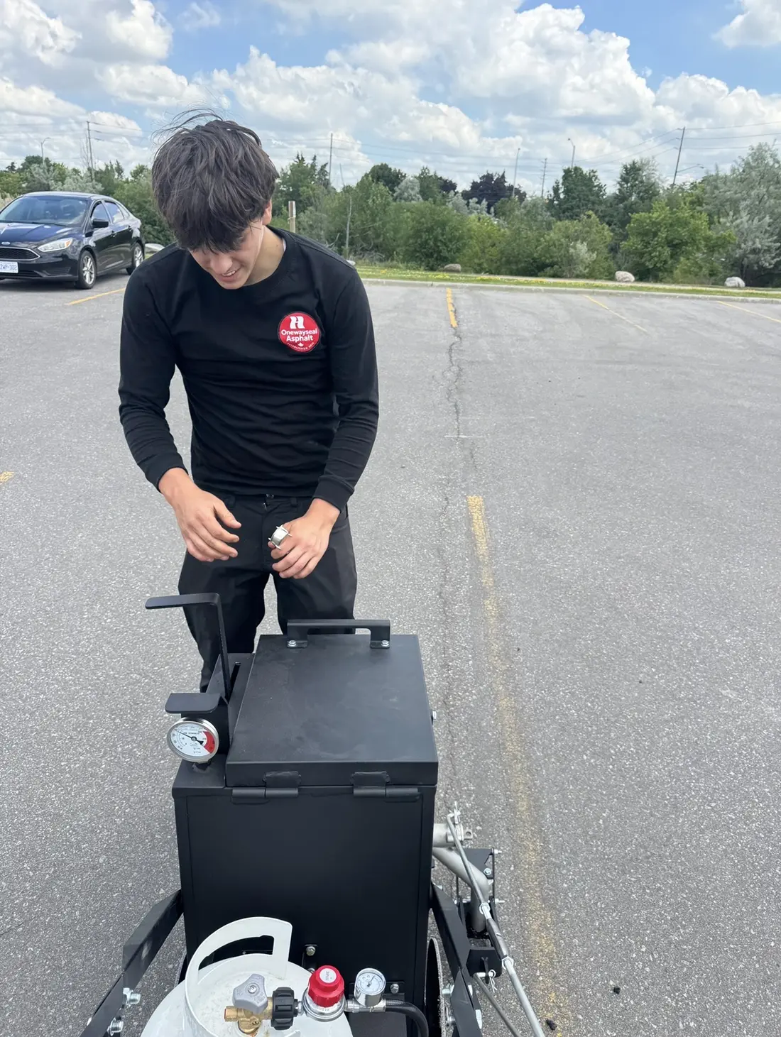 Oneway Asphalt Seal team member preparing commercial crack filling equipment
