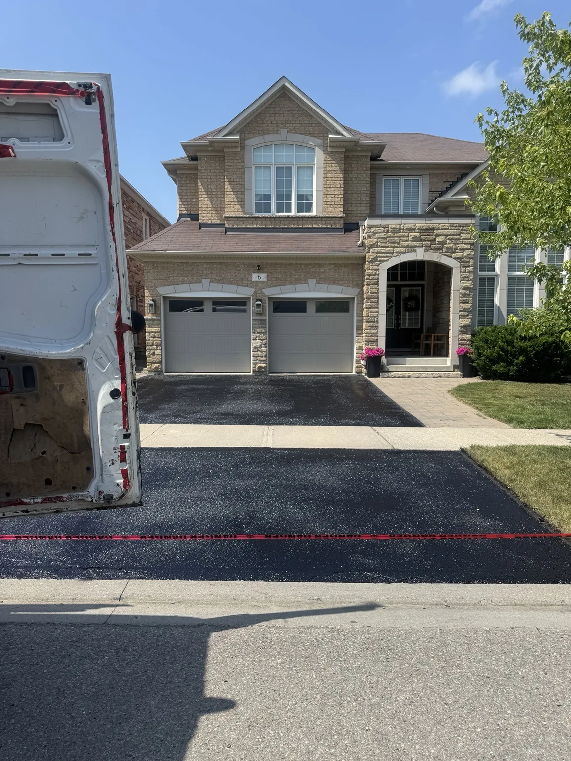 Fresh oil-based driveway sealing on a double garage home